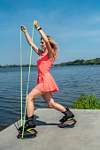 beautiful young healthy girl with good physical condition trains on springs near a simple lake