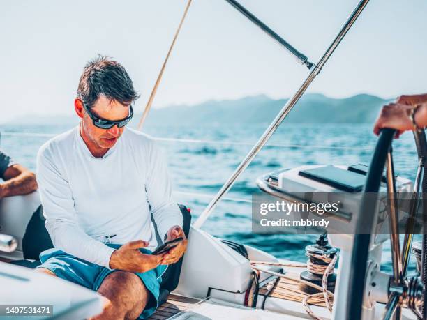 businessman with smart phone on sailboat - yachting stock pictures, royalty-free photos & images