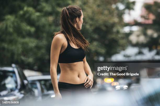 female athlete looking over shoulder on city street - abdomen stock-fotos und bilder