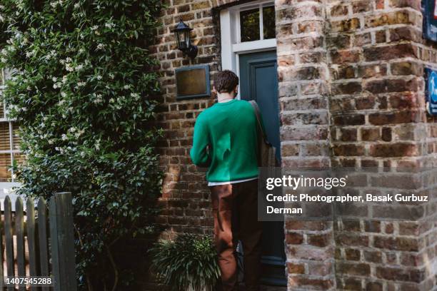 a young man leaving home in the morning, locking the door with his keys - door way stock pictures, royalty-free photos & images