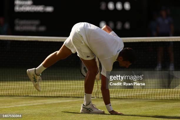 Novak Djokovic of Serbia touches the grass as he celebrates match point against Cameron Norrie of Great Britain during the Mens' Singles Semi Final...