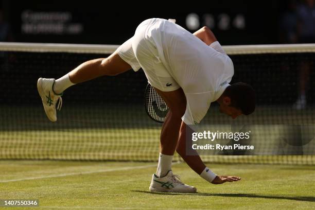 Novak Djokovic of Serbia touches the grass as he celebrates match point against Cameron Norrie of Great Britain during the Mens' Singles Semi Final...