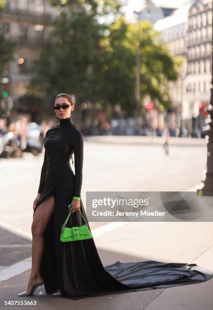 Sabina Jakubowicz seen wearing black sunglasses from Balenciaga, a black high neck / long sleeves slit long dress from Balenciaga, a neon green...