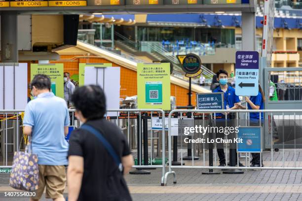 People walk past the QR code for the LeaveHomeSafe Covid-19 contact-tracing app and vaccine pass sign at the Happy Valley Racecourse on July 6, 2022...