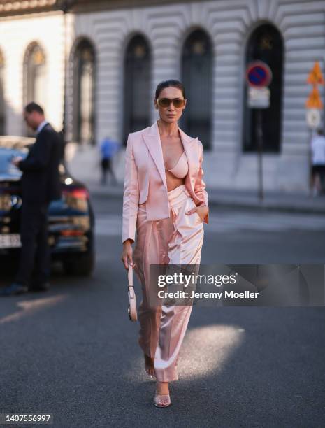 Sabina Jakubowicz seen wearing gold/brown sunglasses from Fendi, a light pink satin bralette/bra underwear from Fendi, a light pink satin/silk short...