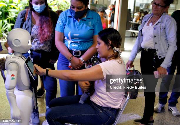 An advisor guides users to interact with the “Pepper” robot during a trial of robotic assistants Pepper and James at Medellin Town Hall on July 08,...