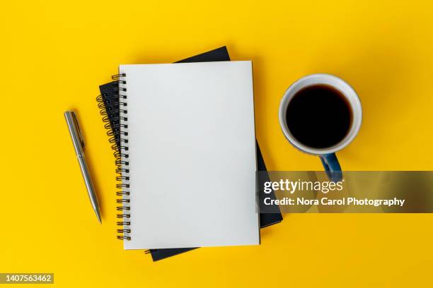 note pad, pen and cup of coffee on yellow background - bureau en open space stockfoto's en -beelden