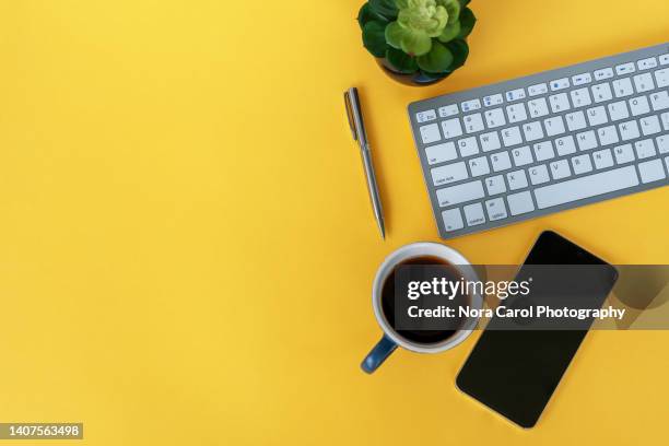 office desk on yellow background with copy space - table top view stock-fotos und bilder