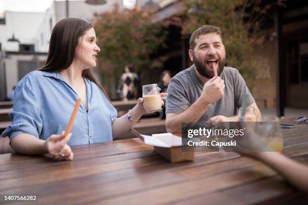 friends chatting and eating churros - churros stock pictures, royalty-free photos & images