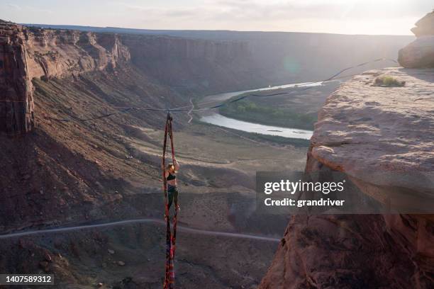 junge frau, die aerial silks oder spanish rope in moab, utah aufführt - luftakrobat stock-fotos und bilder