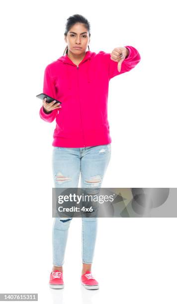 generation z female standing in front of white background wearing canvas shoe and using mobile phone - female worried mobile imagens e fotografias de stock