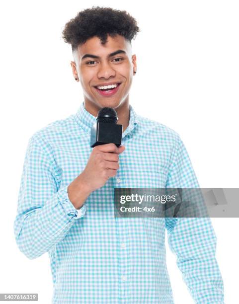 generation z teenage boys newscaster standing in front of white background wearing pants and holding microphone - microphone white background stockfoto's en -beelden