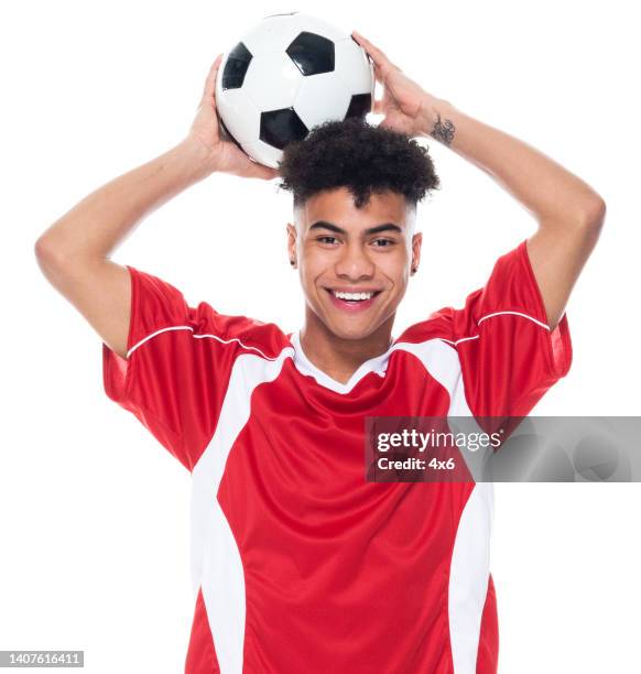 afro-américaine ethnique adolescent garçons athlète debout devant le fond blanc portant l’uniforme de football et tenant le ballon de football et jouant au football - sport et utilisant le ballon de sport - tenue de football photos et images de collection