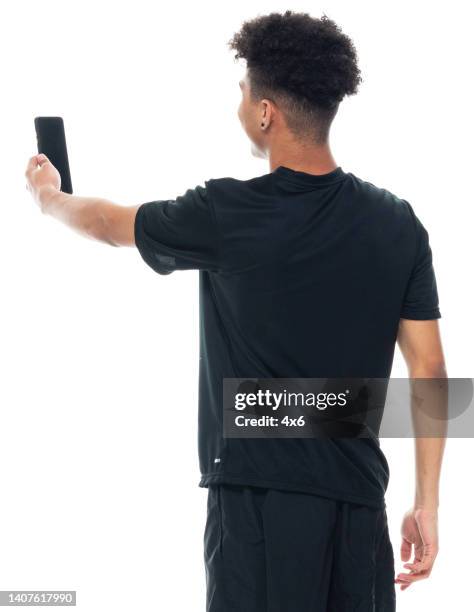 african ethnicity teenage boys photography standing in front of white background wearing sports clothing and using smart phone - taking selfie white background stock pictures, royalty-free photos & images