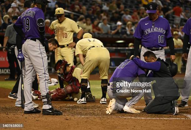 Jose Iglesias of the Colorado Rockies and catcher Jose Herrera of the Arizona Diamondbacks are both attended to by their athletic trainers after a...