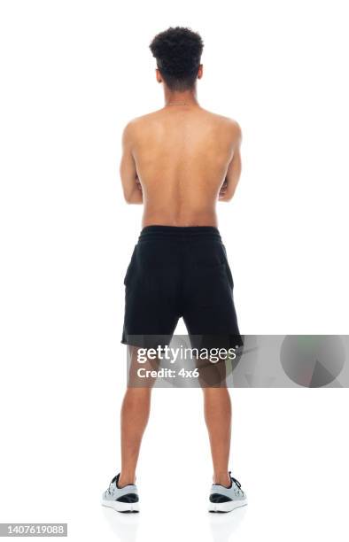 afroamerikanische ethnizität junger mann, der vor weißem hintergrund mit sportschuh steht - schwarze shorts stock-fotos und bilder