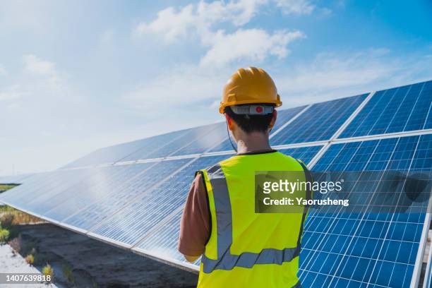 one male engineer checking the solar panel with digital tools - power station stock-fotos und bilder