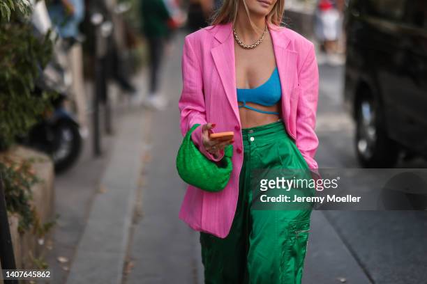 Guest wears white latte sunglasses, a pink linen oversized blazer jacket, gold earrings, a gold large chain necklace, a blue ribbed wool V-neck laces...