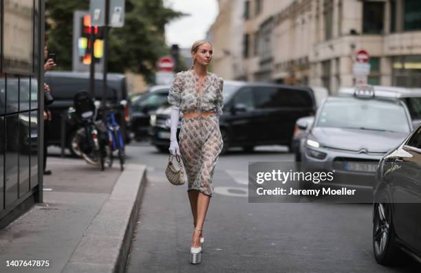 Leonie Hanne wears a gold large pendant earrings from Fendi, a beige with gray chain F monogram print pattern ruffled / puffy short sleeves / cropped...