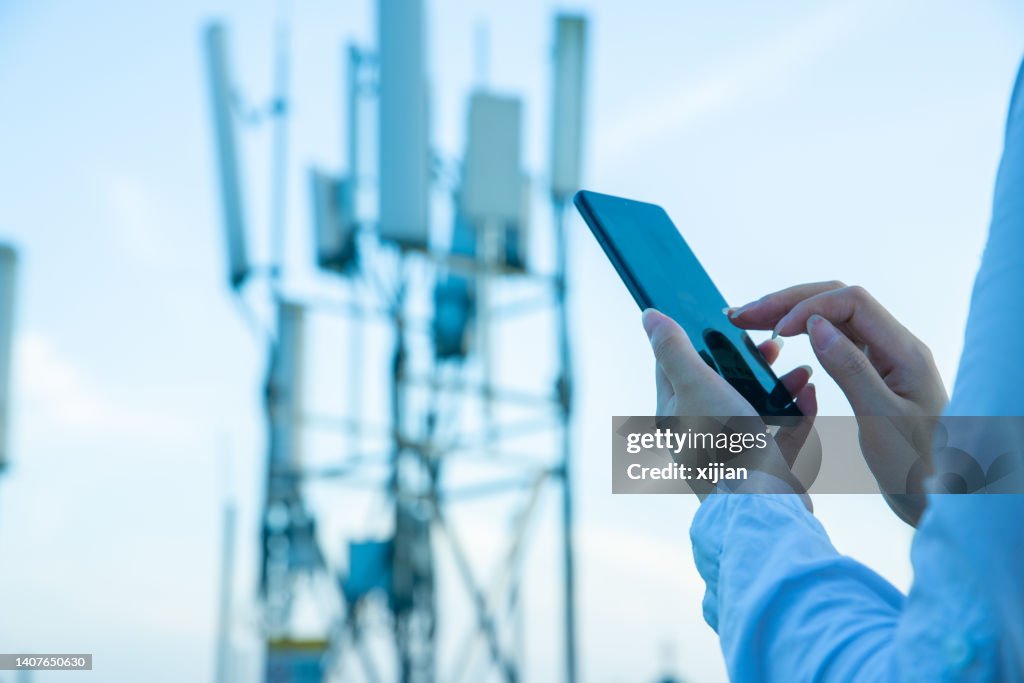 Human hand using mobile phone near 4G,5G communications tower