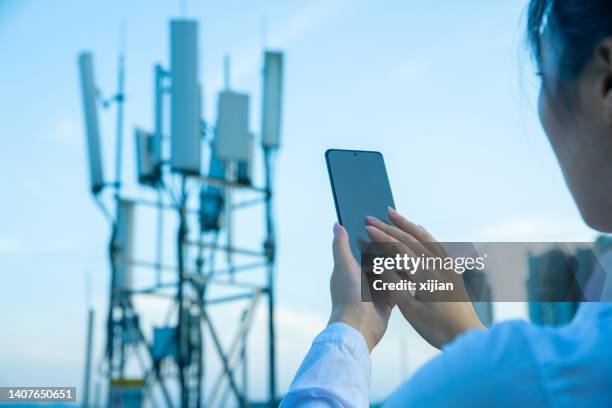 human hand using mobile phone near 4g,5g communications tower - 4g stock pictures, royalty-free photos & images