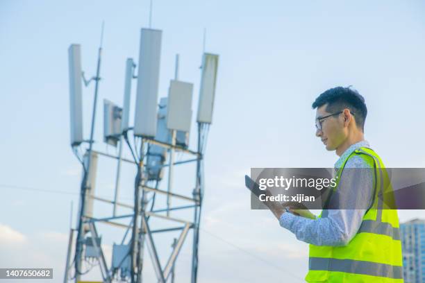 engineer working near communications tower - power mast stock pictures, royalty-free photos & images
