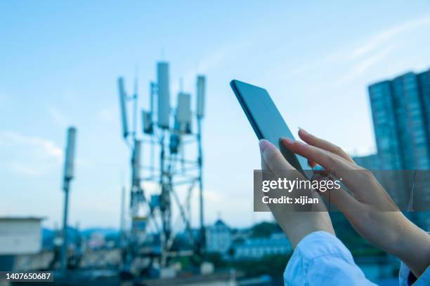 human hand using mobile phone near 4g,5g communications tower - 4g stock pictures, royalty-free photos & images