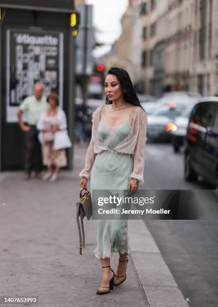 Jessica Wang seen wearing grey bag, green dress, sheer top, heels with logo print outside Fendi, during Paris Fashion Week - Haute Couture Fall...