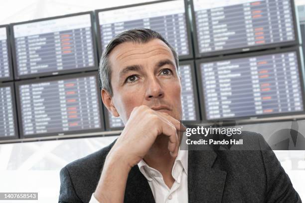 thoughtful businessman is worried about late arrivals at airport / railway station - departure board front on fotografías e imágenes de stock