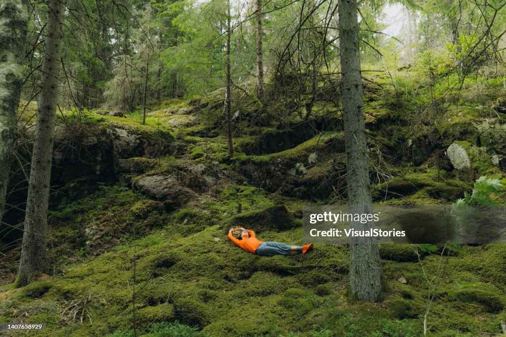 Frau, die die Natur Schwedens betrachtet, entspannt sich auf Moos im Wald