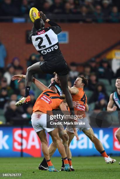 Aliir Aliir of Port Adelaide flies over Harry Himmelberg and Toby Greene of the Giants but doesn't hold the mark during the round 17 AFL match...