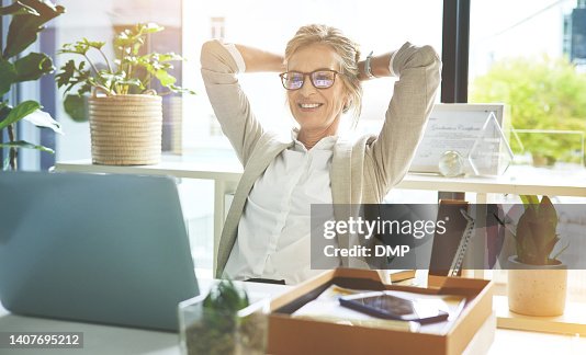 Happy mature manager satisfied and relieved to be done with deadlines and tasks. Business woman feeling accomplished and enjoying a relaxing break to stretch with hands behind her head in an office. Happy mature manager satisfied and relieved to be done with deadlines and tasks. Business woman feeling accomplished and enjoying a relaxing break to stretch with hands behind her head in an office.