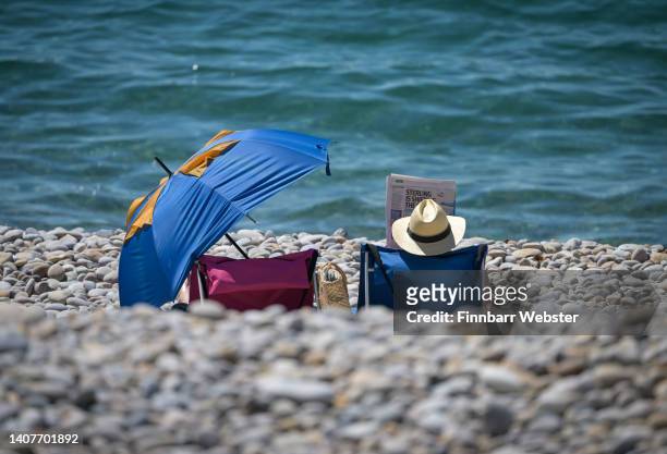 Man reads a newspaper at Chesil beach on July 09, 2022 in Portland, England. Britain will experience a heatwave this week as temperatures in some...