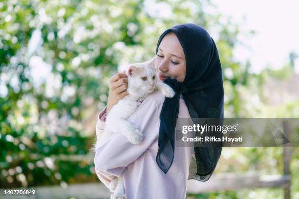 femme hijab avec un beau chat dans le bras - indonesia muslim fashion photos et images de collection