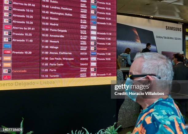 Mask-clad man walks in front of arrivals board showing two of 28 flight cancellations planned for the day at Terminal 1 arrivals hall in Humberto...