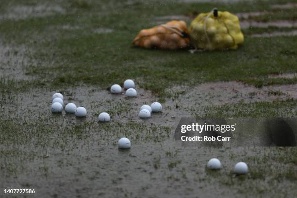 Golf balls are seen in puddles on the practice range after play was suspended due to rain during the third round of the Barbasol Championship at...