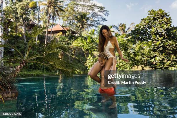 young couple playing around in luxury resort  infinity pool during a vacation, surrounded by tropical plants. - hotel fun bildbanksfoton och bilder