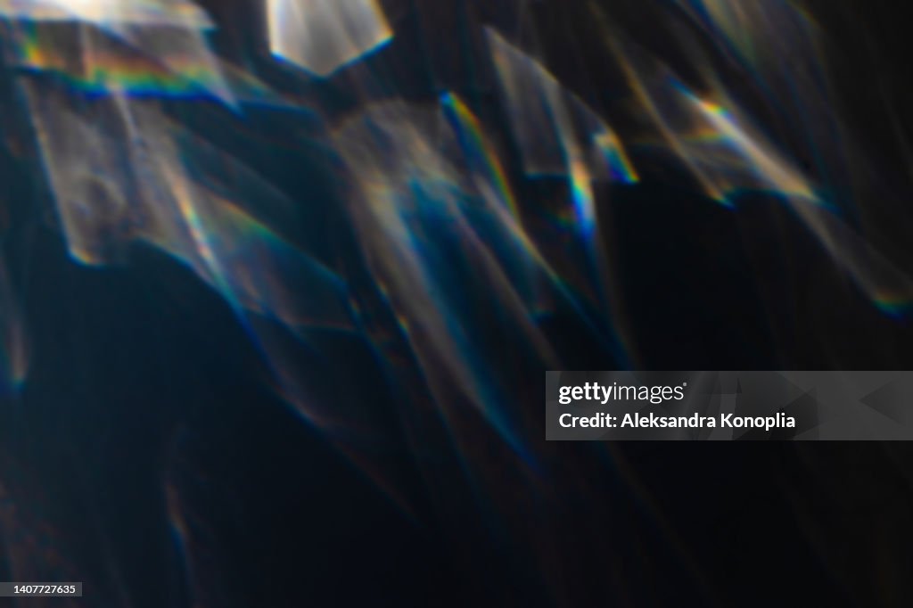 Colourful rainbow light leaks texture on black background