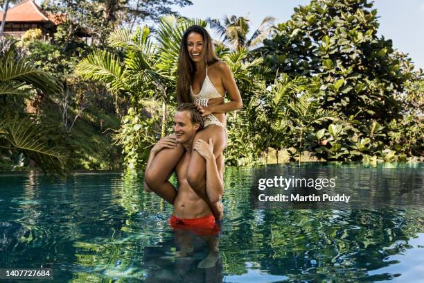 young couple playing around in luxury resort  infinity pool during a vacation, surrounded by tropical plants. - couple paysage asie photos et images de collection