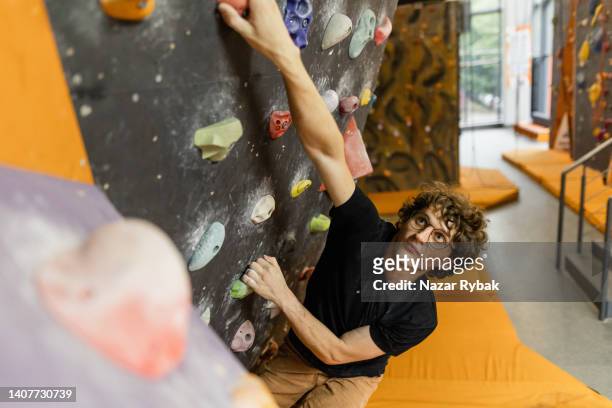 the man climbing on the bouldering wall - bouldering stock pictures, royalty-free photos & images