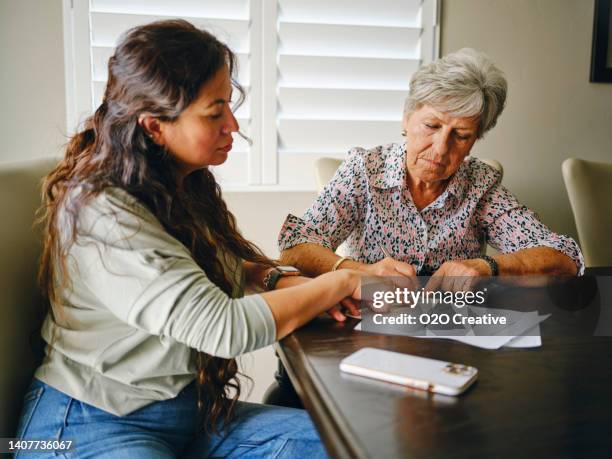 woman helping a senior wtih documents - bill assistance stock pictures, royalty-free photos & images