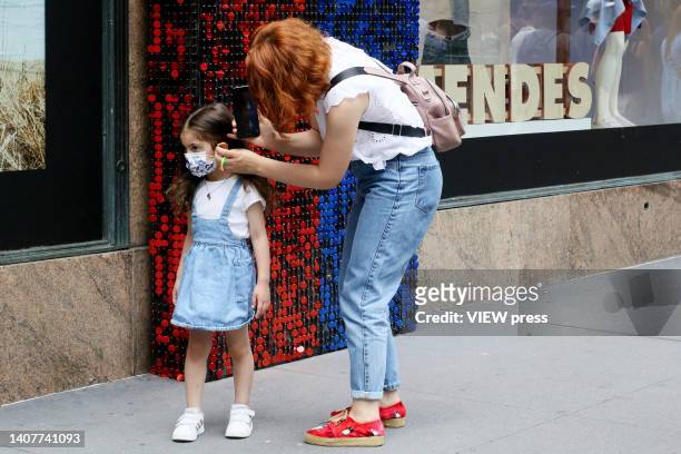 Woman helps to wearing a mask to a girl, on July 09, 2022 in New York. New York City public health officials urged people to return to mask-wearing...