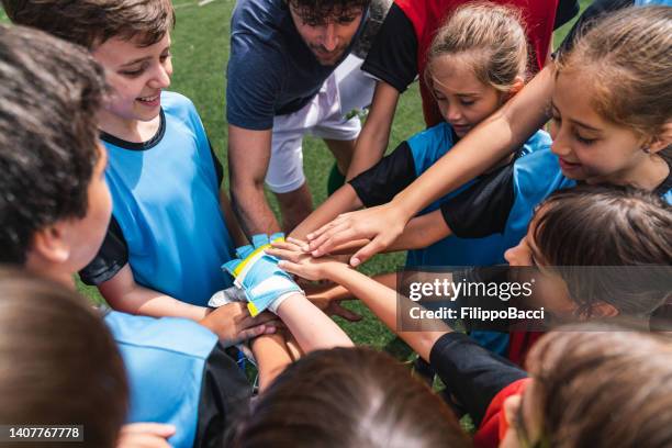 試合前に円で手を合わせた女性と男性の子供のサッカー選手 - ジュニアレベル ストックフォトと画像