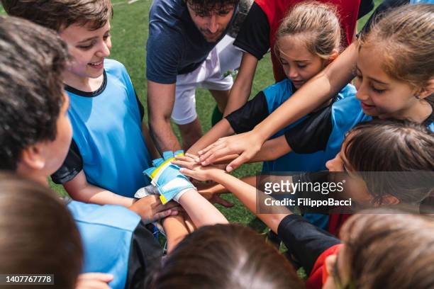 female and male kids soccer players together with hands in circle before a match - team player stockfoto's en -beelden