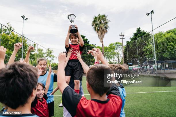 group of kids celebrating together with the coach the winning of a competition on a soccer field - title nine imagens e fotografias de stock