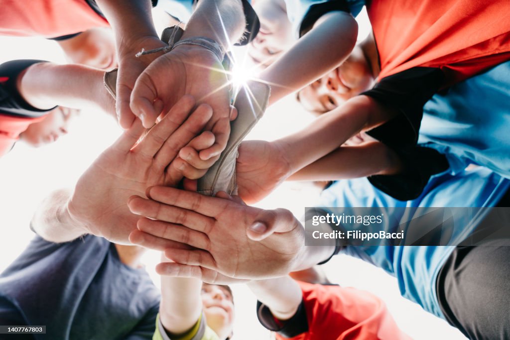 Baixa vista do ângulo da equipe da escola do futebol dos miúdos que huddling junto