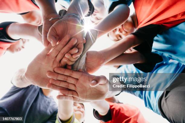 low angle view of kids football school team huddling together - children sport imagens e fotografias de stock