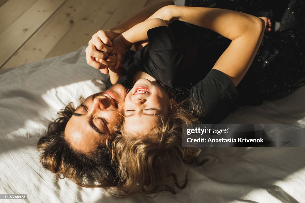 Beautiful mother and daughter having fun in bed.