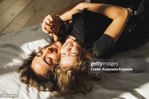 beautiful mother and daughter having fun in bed. - simple living room stock pictures, royalty-free photos & images