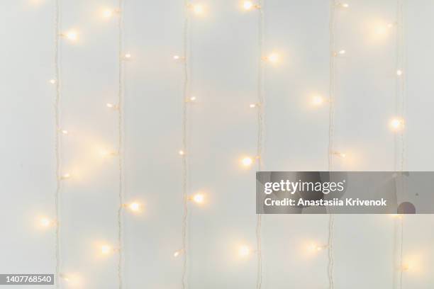 white wall christmas background with shiny lights. - hanging christmas lights stock-fotos und bilder